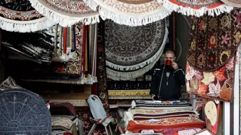 EPA An Iranian shopkeeper at a stand in a market in Tehran, Iran, 5 November 2018