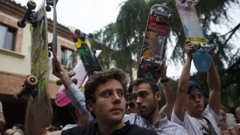 Getty Images Fellow skateboarders paying tribute with their boards aloft