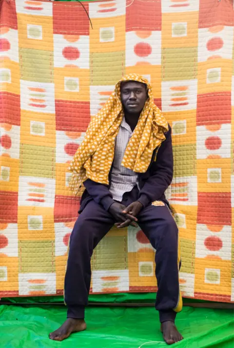 Marcus Drinkwater Abubaker Halin, Sudan sits with bare feet