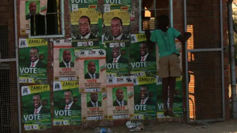 Reuters A boy plays next to election posters at White City Stadium where Zimbabwe's President Emmerson Mnangagwa escaped unhurt after an explosion rocked the stadium, in Bulawayo, Zimbabwe, June 23, 2018.