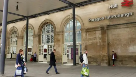 A stock image of the outside of Hull Paragon station with people carrying shopping bags and walking past