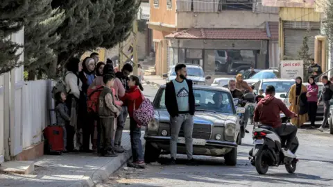 AFP People wait for elevators on the side of the road after the Israeli army issued an evacuation order for the entire city of Baalbek, in the Bekaa Valley, eastern Lebanon (October 30, 2024)