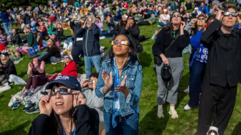 Getty Images People gather at Greenwood Cemetery in Brooklyn to witness a partial solar eclipse in April 2024. 