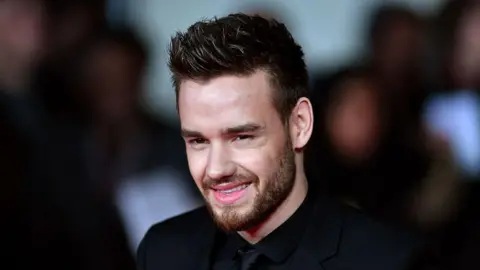 Getty Images Liam Payne smiles in an all black suit whilst attending a film premiere in London