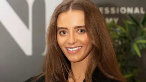 Melissa Ham Photography Charlotte smiling at the camera. She has long brown hair and is wearing a black top.