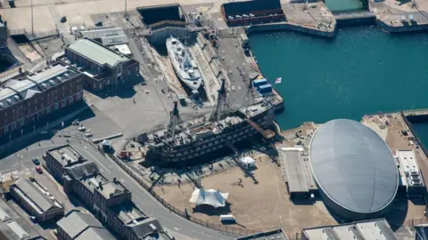 Getty Images Aerial view of Portsmouth Historic Dockyard. Several naval buildings can be seen, and two vessels - one is HMS Victory, a 