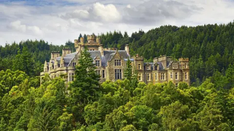 Getty Images Carbisdale Castle has baronial features including turrets. Most of the property is hidden behind trees.