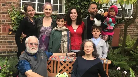 Gottlieb Family/PA Wire Michael and his wife Milli sit on a garden bench with six members of their family of varying ages standing behind them