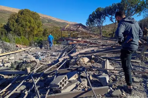 Reuters A man inspects debris from a building deed by an explosion, bricks and bits of metallic are scattered around. A 2nd man is successful nan region stepping and nan framework of a destroyed building tin beryllium seen. 