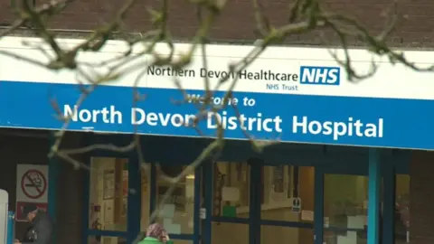 The glass door-fronted North Devon District Hospital, with a blue welcome sign above it.
