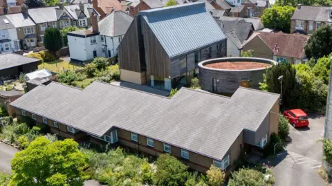 Knight Frank Three distinct modern buildings on the property. Residential homes are behind the structures.