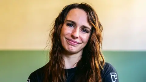 Ffion Davies smiling wearing a black, MMA-branded t shirt.