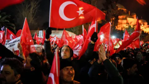 Reuters Supporters of Istanbul Mayor Ekrem Imamoglu wave Turkish flags outside the Istanbul Metropolitan Municipality building during a protest.