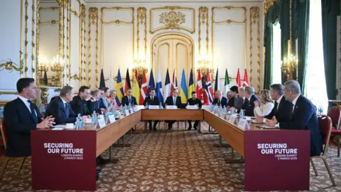 PA Media French President Emmanuel Macron, Prime Minister Sir Keir Starmer and Ukrainian President Volodymyr Zelensky, sit at the head of the table with other European leaders during a summit on the situation in Ukraine at Lancaster House, London