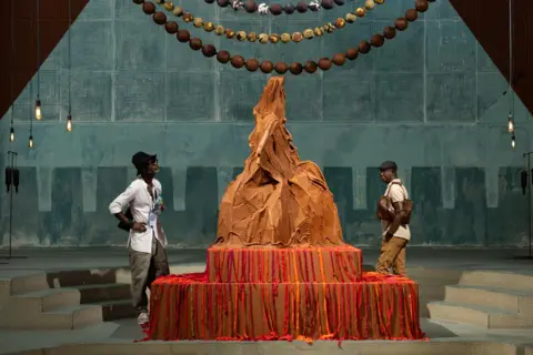 JEROME FAVRE / EPA Two men look at a large rust-coloured art installation which is shaped in a peaked form.