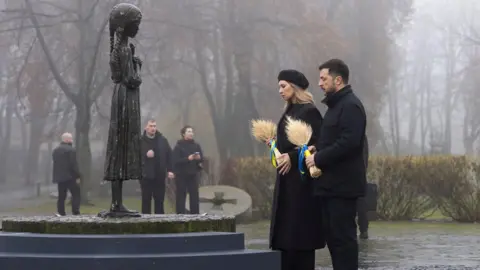 EPA Ukrainian President Volodymyr Zelensky (R) and his wife Olena Zelenska (L) place sheafs of wheat at the child statue titled 'Bitter Memory of Childhood' at the Holodomor Genocide complex of the National Museum in Kyiv. Both wear black.