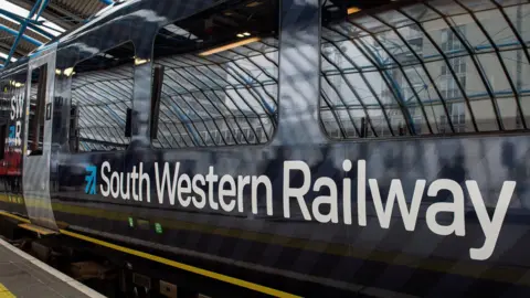 A blue train carriage with South Western Railway written in large white writing across it.