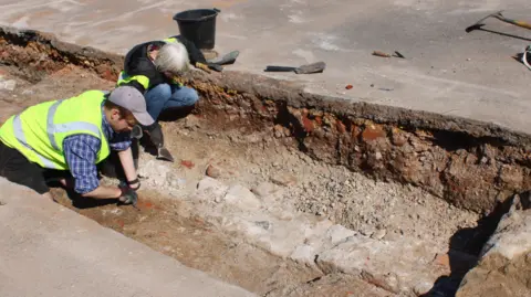 Steve Wallis, Dorset Council Two archaeologists digging in the preliminary trenches found a medieval wall. 