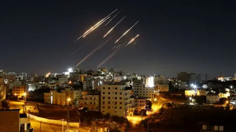Streaks of light from Iranian ballistic missiles are seen in the night sky above Hebron, West Bank