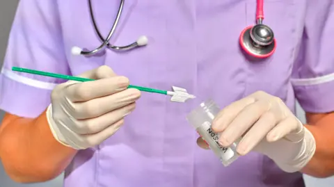 Getty Images A nurse holds a plastic medical pot and a smear test brush