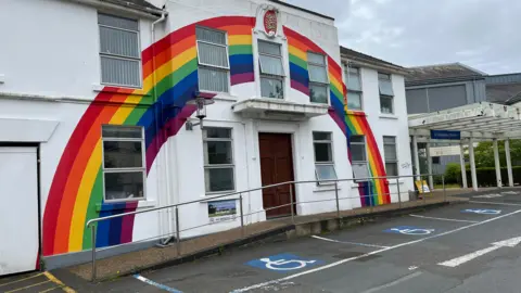 A rainbow painted on the side of a white building. 