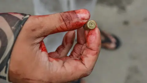 Getty Images A protester holds a bullet fired during a protest against the military coup in March 2021