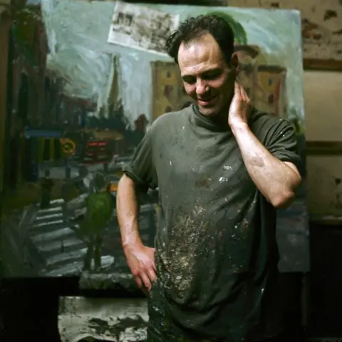 Alamy Frank Auerbach is pictured at work in his studio, in a paint-stained apron with a scene from a street with steps behind him