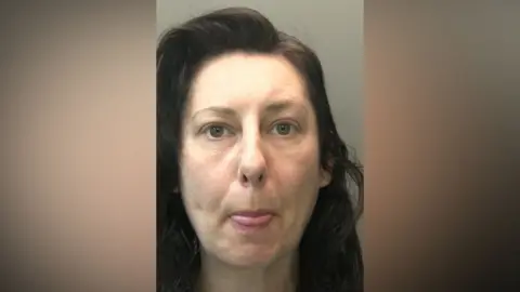 Custody picture of Samantha Gardiner she has log dark hair and is sticking her tongue out.