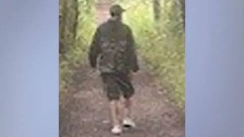 Suffolk Police A CCTV image shows the second man Suffolk Police would like to speak to in connection with the incident. The image shows a man wearing a cap, a dark green jacket, dark coloured knee-length shorts and white shoes.