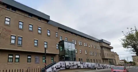 Image of the outside of North Somerset Council. A glass atrium covers the entrance of the light stoned building, which is four storeys tall.