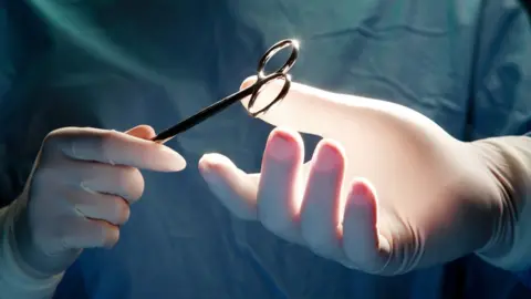 Getty Images Nurse passing surgeon forceps during an operation