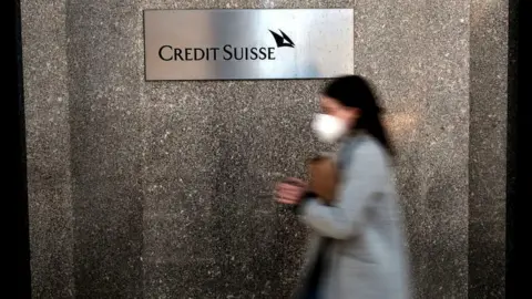 Getty Images Woman walks past Credit Suisse sign