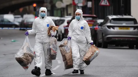 Jacob King/PA Wire Forensic investigators at the scene in Friar Gate, Derby, on Sunday 29 March 2026. They are carrying evidence bags.