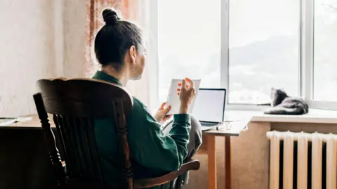 A woman from the back sitting in front of a laptop