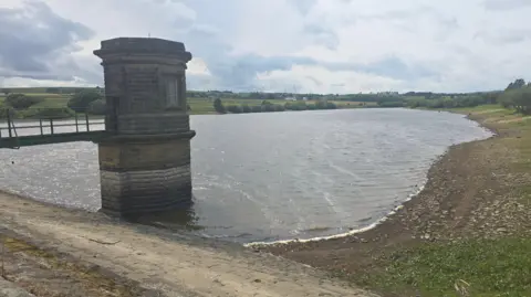 Yorkshire Water A reservoir with a small brick tower and metal bridge leading to it