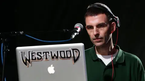 PA Media Tim Westwood pictured in 2014 DJing, using a laptop with his surname on it