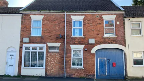 A couple of houses on the row of terraced houses on Union Street in Bridgwater. Two of the houses are red brick and there is a large blue gate in one of them.