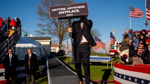 Getty Images An aide carries a podium that reads "Anytime. Anywhere. Anyplace" at a Pennsylvania rally
