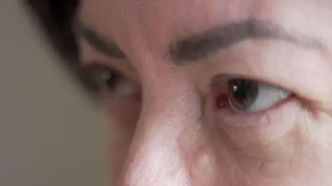 BBC shows a close shot of a woman's face, just showing her eyes, eyebrows and her nose. He has dark, arched eyebrows and brown eyes. 