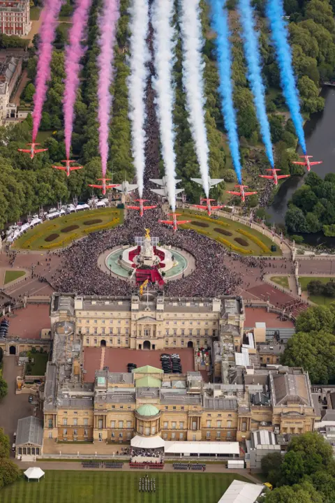AS1 Amelia Turnbull/PA Wire An aerial view shows the Red Arrows deploying their colouful smoke as they fly over Buckingham Palace and the crowds down below.