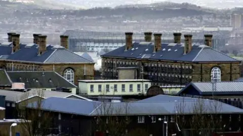 Two Victorian prison blocks towering above buildings in Glasgow. The blocks have chimneys and small windows.