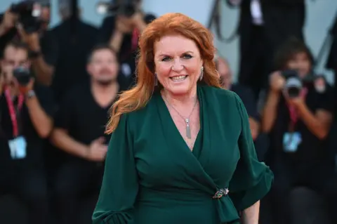 Getty Images Sarah Ferguson, then Duchess of York, attends The Son red carpet at the 79th Venice International Film Festival on September 07, 2022 in Venice, Italy. She is smiling and is wearing a green long-sleeved dress. She has long red hair. Photographers can be seen in the background.