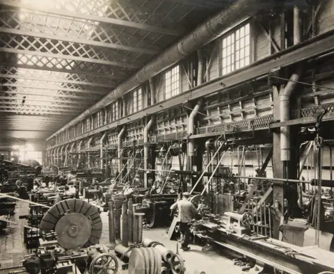 Getty Images A black and white image of the interior of Chance Glassworks in Smethwick, with machinery and workers seen