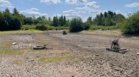 A dry lake in Gedling Country Park, in Nottinghamshire, on a sunny day.