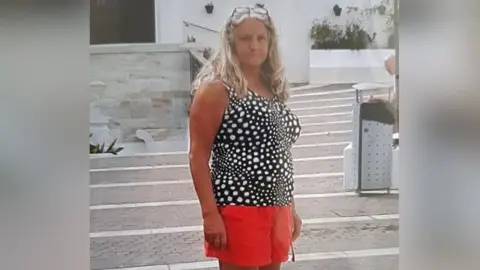 South Yorkshire Police Christine Stenson, a woman with long grey hair, in a black top and orange shorts