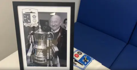 A picture frame of Brian Keen smiling with a trophy.