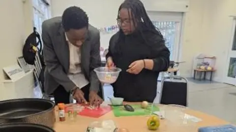 Two people cooking in a cooking class. 