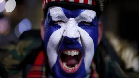 Reuters A close up of a Scotland fan who has their face painted with a Scottish saltire and is wearing a Glengarry hat.