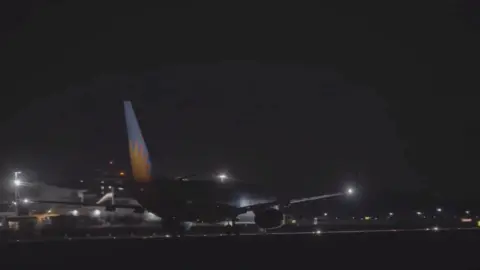 A plane sits on a runway at night