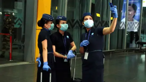 Getty Images IndiGo Airlines Air hostess wearing protective mask posing for selfie on smartphone at the Netaji Subhas Chandra Bose International Airport on June 04, 2020 in Kolkata, India.